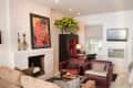 Living room with beige sofa, red armchairs, white brick fireplace, vibrant artwork, and a TV above an air conditioner.