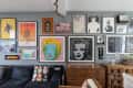 Gallery wall with colorful pop art, including Marilyn Monroe prints, above a dark sofa and wooden cabinet.