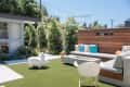 Modern patio with gray sectional, colorful cushions, fire pit, white chair, and decorative rabbit on artificial grass.