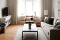 Living room with beige sofa, modern chandelier, coffee table, TV stand, and armchair by a window with sheer curtains.