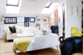 Bright loft living room with white sofas, skylights, wall art, a yellow chair, and a black pig-shaped decor piece.