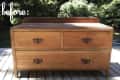 Wooden dresser with three drawers and ornate handles on a deck, labeled "before."