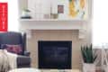 Living room with a beige fireplace, abstract art, gray armchair, and potted snake plant.