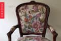 Ornate wooden chair with floral upholstery in pink, blue, and green tones.