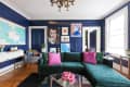 Living room with blue walls, green velvet sofa, pink cushions, wall art, and a map.