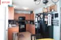 L-shaped kitchen with wooden cabinets, black appliances, and a fridge covered in magnets and notes.