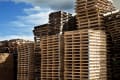 Stacks of wooden pallets under a partly cloudy sky.