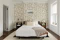 Bedroom with floral wallpaper, white bedding, wooden nightstands, and a framed picture above the bed.