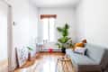 a minimalist living room is sparse except for a gray couch and a large houseplant