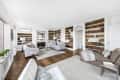 Spacious living room with built-in bookshelves, two gray sofas, a fireplace, and a glass coffee table on a hardwood floor.