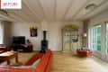 Living room with red leather sofas, wooden floor, TV, glass cabinet, and a wood-burning stove.