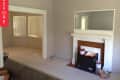 Living room with beige walls, white fireplace, large mirror, and paint cans on the floor.