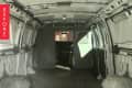 Empty interior of a white cargo van with metal partition and exposed wiring.