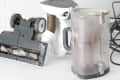 Disassembled vacuum cleaner with dust canister, hose, and brush head on a white surface.