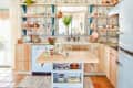 Vintage kitchen with open shelves, floral tiles, wooden cabinets, and a central island with breakfast items.