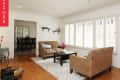 Living room with beige sofas, black coffee table, large windows, and view into dining area.