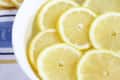 Lemon slices floating in a white bowl of water on a striped cloth.