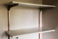 Two white wall-mounted shelves with copper brackets in a corner.