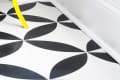 Black and white geometric floor tiles with a yellow ladder in a white room corner.