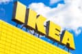 Large yellow IKEA sign on a building with a grid pattern against a blue sky with clouds.