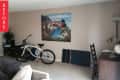 Living room with a bicycle, desk, chair, and large wall art of a coastal town.