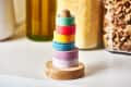 Stack of colorful washi tapes on a wooden holder, with jars of grains and pasta in the background.