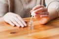Person applying clear nail polish on a wooden table.