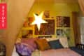Cozy bedroom with star-shaped light, colorful pillows, and eclectic wall art on a yellow wall.