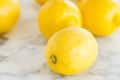 Fresh lemons scattered on a marble countertop.