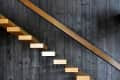 Floating wooden staircase against a dark wood-paneled wall.