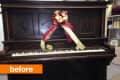 Antique upright piano with a red and gold ribbon bow on top.