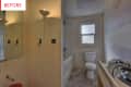 Small bathroom under renovation with exposed wiring, a floor lamp, toilet, bathtub, and unfinished walls.