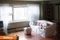 Living room with white sofa, striped pillows, sheer curtains, and a small ottoman near a window.