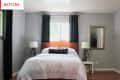 Bedroom with gray walls, wooden headboard, white bedding, black curtains, and two bedside lamps.