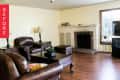 Living room with brown leather sofas, wooden coffee table, brick fireplace, and TV on a stand near a window.