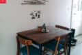 Small dining area with a wooden table, two chairs, wall art made of sticks, and small decor items.
