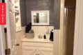 Small bathroom with white vanity, mirror, and gray walls, featuring a basket with towels and a soap dispenser.