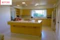 Yellow kitchen with tiled island, wooden cabinets, and large window with garden view.