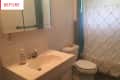 Small bathroom with a white sink, mirrored cabinet, toilet, and textured shower curtain.