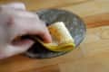 Hand polishing a metal surface with a banana peel on a wooden table.