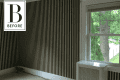 Empty room with black and white striped wallpaper, large window, and radiator cover.
