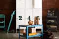 White numbered lockers with a clock, teal chair, blue cart, and decor items in an industrial-style room.