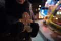 Person holding a gingerbread cookie at a festive night market with colorful lights in the background.