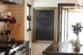 Rustic kitchen with a large stove, wooden island, stools, and a chalkboard with "Life is Good!" written on it.