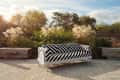 Striped black and white sofa on a patio with tall grasses and trees in the background.