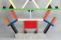 Colorful geometric bookshelf with red drawers, angled supports, and a speckled base.