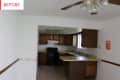 Dated kitchen with brown cabinets, yellow countertops, and a ceiling fan.