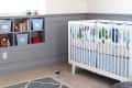Nursery with striped walls, white crib, owl plush, bird mobile, and shelves with colorful books and toys.