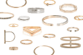 Various gold and silver rings and bracelets with geometric designs and gemstone accents arranged on a white background.