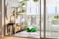 Laundry room with ironing board, hanging clothes, potted plants, and storage shelves against a white brick wall.